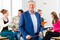 Professor vor Studentengruppe Das Bild zeigt einen Professor, der vor einer Gruppe Studenten steht