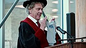 Prof. Dr. Gerhard Raab präsentiert im Rahmen seiner Ansprache ein besonderes „Mitbringsel“ für Rizwan Zafar, einen der Graduierenden, der aufgrund der Geburt seines Sohnes im Juni in Deutschland geblieben ist und an der Zeremonie per Videoschalte teilnimmt